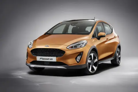 Pomarańczowy Ford Fiesta MK9 z czarnymi akcentami i relingami dachowymi, gotowy na miejskie przygody.