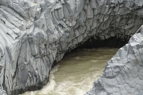Die Alcantara Schlucht in Sizilien zeigt faszinierende Basaltsäulen, die von einem türkisfarbenen Fluss umspült werden.