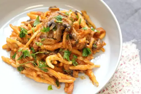 En krämig pasta boscaiola med svamp och persilja, serverad i en vit skål.