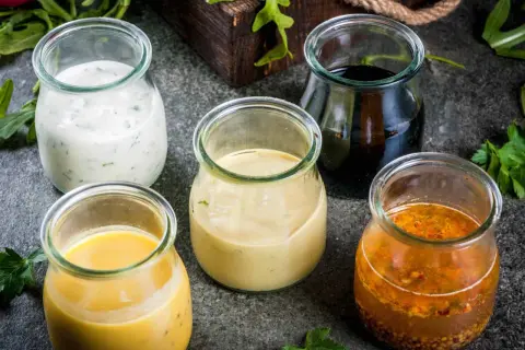 Fem burkar med olika dressingar, från krämig vit till mörk balsamico. Vilken är godaste dressingen till sallad?