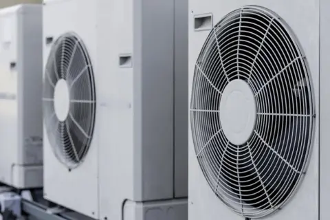 Rząd białych jednostek zewnętrznych, gdzie pompa ciepła i klimatyzacja pracują razem, zapewniając komfort.