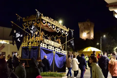 Serata a Porto Recanati con processione notturna e la torre dell'orologio illuminata.