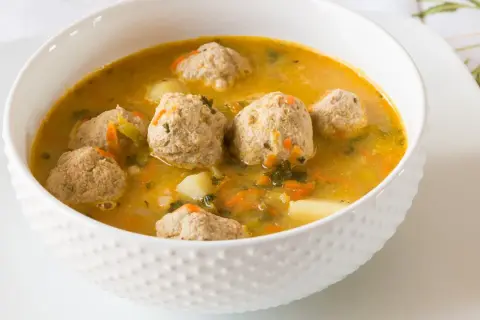 Zupa klopsowa babci: aromatyczny bulion z klopsikami, ziemniakami i warzywami. Smak dzieciństwa w miseczce.