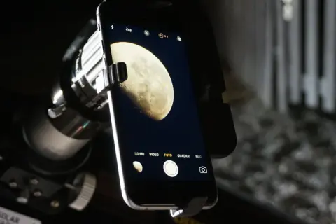 Telefon z aparatem uchwycił zdjęcie księżyca w pełni, widocznego przez teleskop.