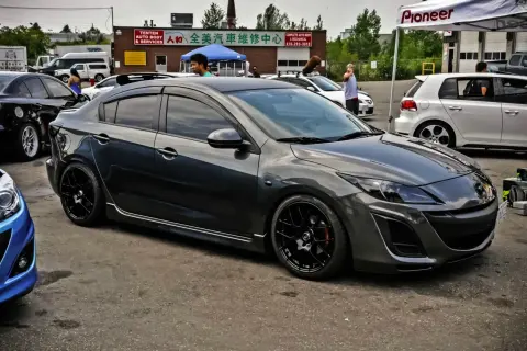 Mörkgrå Mazda 3 med svarta fälgar, redo för en tur. Kanske ett litet **Mazda 3 problem** med däcken?