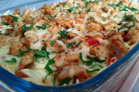 Zapiekanka z makaronem, kurczakiem i roztopionym serem, posypana natką pietruszki.