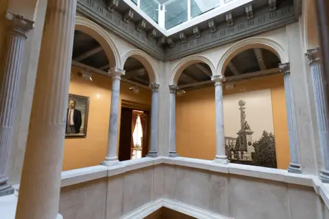 Interior del palacio de Armijo con arcos, columnas y un retrato.