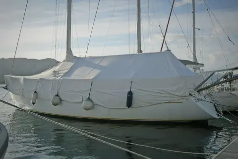Barca a vela coperta con un telo per barca fai da te, pronta per l'inverno.