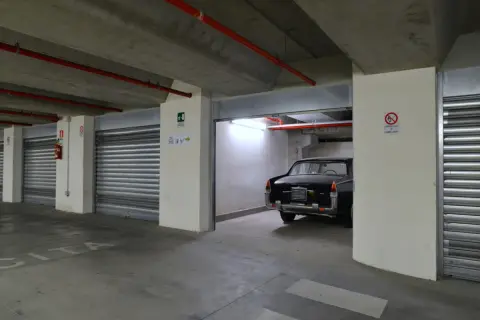 Un'auto d'epoca nera in un garage sotterraneo. Le porte a serranda chiuse e l'illuminazione suggeriscono che affittare garage conviene per proteggere il tuo veicolo.