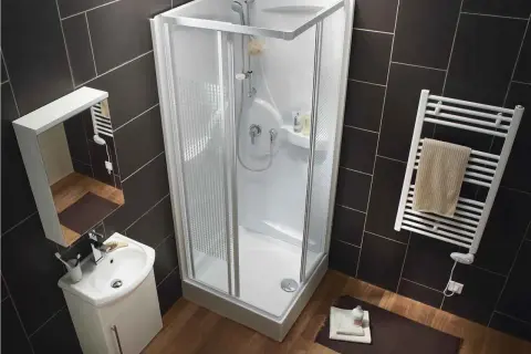 Salle de bain moderne avec une cabine de douche aux dimensions compactes, un lavabo suspendu et un sèche-serviettes.