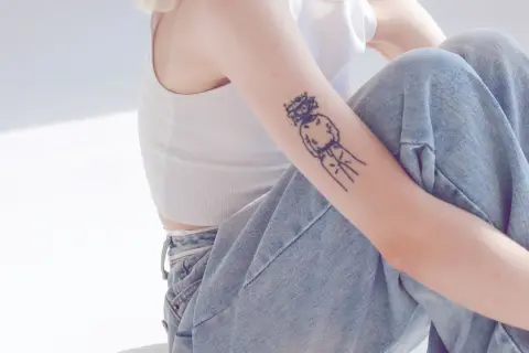 Ein Arm mit einem abstrakten Tattoo, das eine Figur mit Krone zeigt. Ein Beispiel für beste Tattoos, die Persönlichkeit ausdrücken.