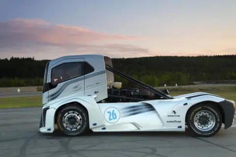 Le camion de course "The Iron Knight" blanc et argenté, numéro 26, sur une piste au coucher du soleil.