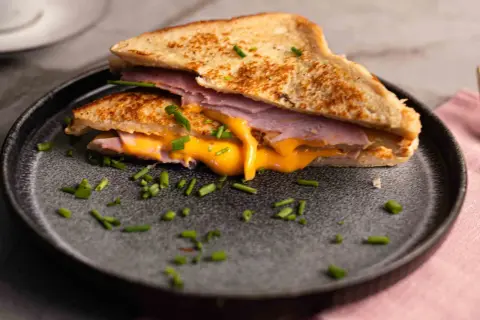 Herzhaftes French Toast mit Schinken und geschmolzenem Käse, garniert mit Schnittlauch.