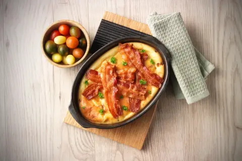 En härlig ugnspannkaka med knaprigt bacon och färska örter, serverad med en skål körsbärstomater.