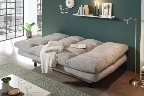 Gemütliches Schlafsofa im Wohnzimmer, ideal zum dauerhaft im wohnzimmer schlafen. Mit Decke und Buch für entspannte Stunden.