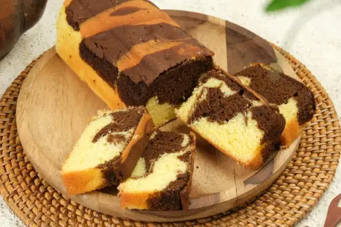 Babka marmurkowa z czekoladą i wanilią, pokrojona na plastry, na drewnianej desce.