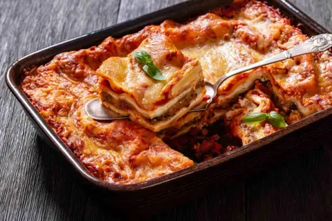 Pyszne lasagne z warzywami, zrumienione i pachnące, podane na drewnianym blacie. Idealne danie na rodzinny obiad.