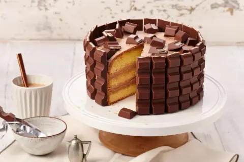 Eine köstliche Kinderriegel Torte, umhüllt von Schokoriegeln und garniert mit Stückchen. Ein Traum für jeden Schokoladenliebhaber!