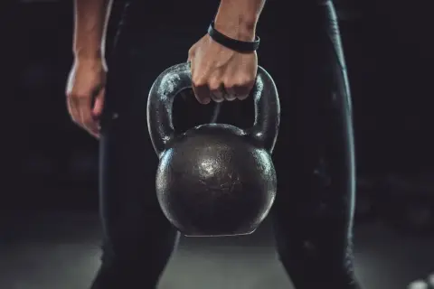 A person's hand grips a kettlebell, ready for a powerful kettlebell boxing workout.