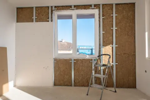 Installazione di sistemi di isolamento termico con lana di roccia e cartongesso, con una scala appoggiata al muro.