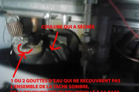 Détail d'une chaudière : une coulure sèche et une petite tache humide près d'un bouchon, peut-être la cause d'une veilleuse chauffage gaz ne tient pas.