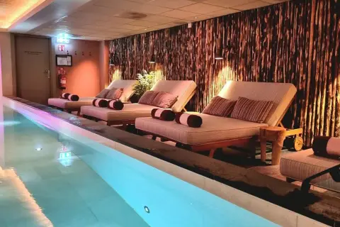 Avslappning vid poolen på ett elite hotell i Borlänge. Bekväma solstolar med kuddar och handdukar står redo vid det upplysta vattnet.