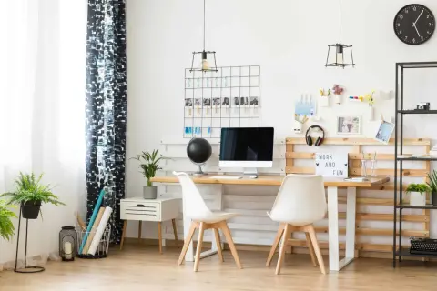 Un moderno angolo smart working con scrivania in legno, sedie bianche, computer e una lavagna luminosa con la scritta "Work and Fun".