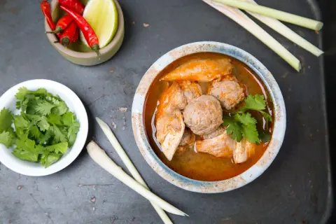 Aromatic tradycyjna zupa tajska z kurczakiem i klopsikami, podana z kolendrą, chili i trawą cytrynową.