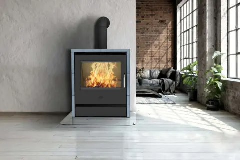 Ein moderner Kamin mit brennendem Feuer, umgeben von einer Wand aus grobem Beton und Ziegeln. Die Frage "was ist Speckstein?" wird durch die Wärme und Gemütlichkeit des Kamins beantwortet.