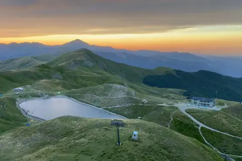 Alba sulle montagne toscane, con un lago alpino e rifugi che ricordano i borghi vicino Abetone.