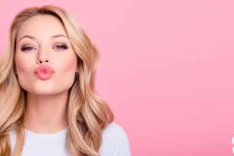 Blondynka z okrągłą twarzą i falowanymi włosami posyła całusa.