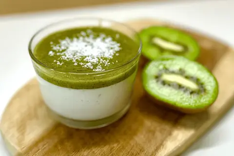 Panna cotta au lait et coulis de kiwi, saupoudrée de noix de coco râpée. Une recette légère et fruitée.