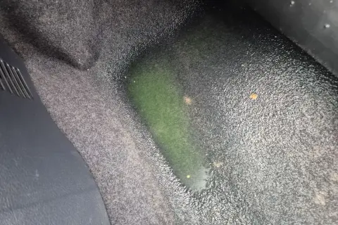 Zielona, mokra podłoga w aucie, prawdopodobnie płyn chłodniczy.