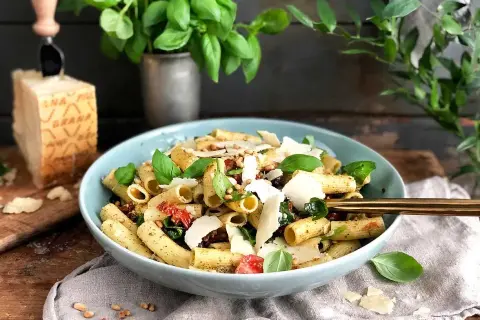 En läcker pastasallad med pesto, soltorkade tomater och färsk basilika, toppad med parmesan.