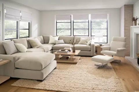 A large, neutral sectional couch is arranged in a cozy living room, showcasing different ways to arrange a sectional couch for optimal comfort and style.