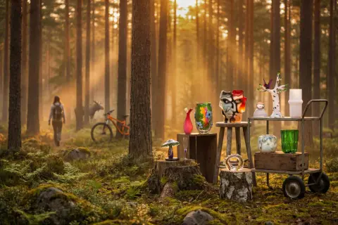 I en solbelyst skog, med en älg och cykel i bakgrunden, visas konstglas som en karta över Glasriket.