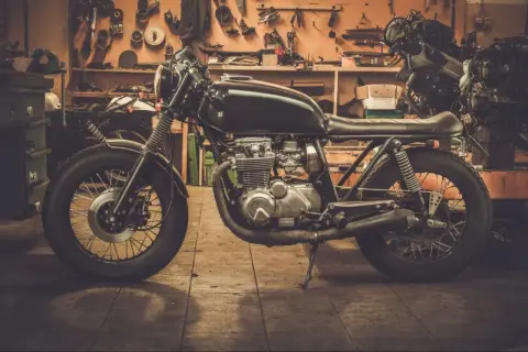 Czarny motocykl typu cafe racer w warsztacie, gotowy do sezonu.