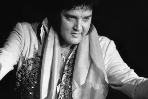 Elvis Presley w błyszczącym stroju, z szalem na szyi. Ciekawe fakty o Królu Rock and Rolla.