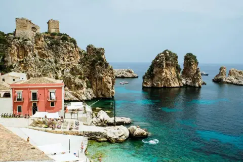 Scopri Castellammare del Golfo: case colorate, rovine antiche su scogliere rocciose e un mare cristallino con faraglioni.