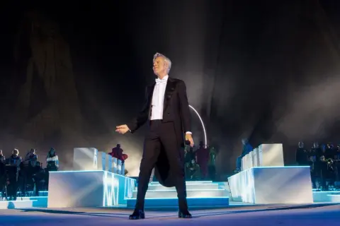 Claudio Baglioni in smoking, sul palco con orchestra e coristi, un momento iconico della sua biografia artistica.
