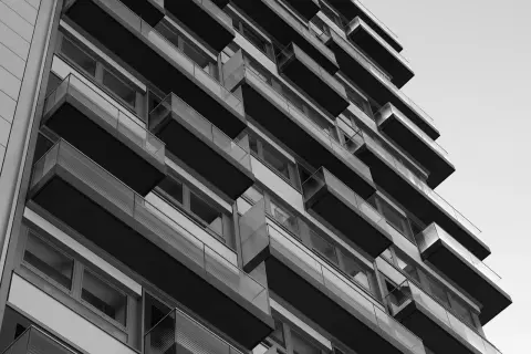 Nowoczesny budynek z balkonami, tworzący geometryczną kompozycję. Widok z dołu, podkreślający architekturę. WM rejestracja.