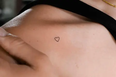 Kleines Herz-Freundschaftstattoo auf der Schulter einer Frau, ein zartes Symbol ewiger Verbundenheit.