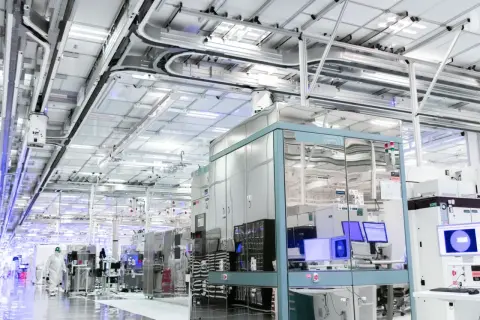 Czysty, nowoczesny zakład produkcyjny, gdzie powstają technologie dla największych firm IT na świecie. W tle widać linie produkcyjne i systemy transportowe.