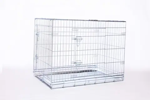 Une cage métal chien vide, prête à accueillir un compagnon. Elle est faite de barreaux argentés et possède un plateau amovible.