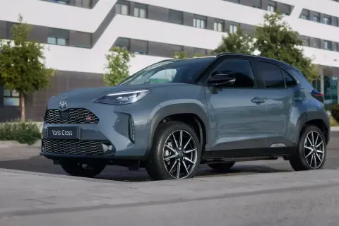 Szary Toyota Yaris Cross GR Sport zaparkowany przed nowoczesnym budynkiem. Zastanawiasz się, ile kosztuje Toyota Yaris?