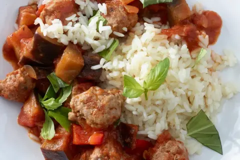 Herzhafte Salsiccia-Zubereitung in der Pfanne mit Auberginen, Paprika und Reis, garniert mit frischem Basilikum.