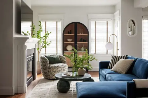 A round coffee table decor features a vase with greenery and a beaded strand, adding a natural touch to the living room.