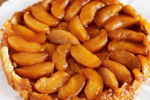 En gyllene tarte tatin med karamelliserade äppelklyftor som glänser. En klassisk fransk dessert som smälter i munnen.