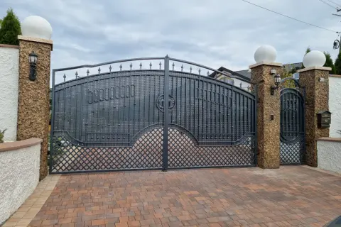 Elegancki montaż bramy dwuskrzydłowej do słupków betonowych. Wjazd wyłożony kostką brukową.