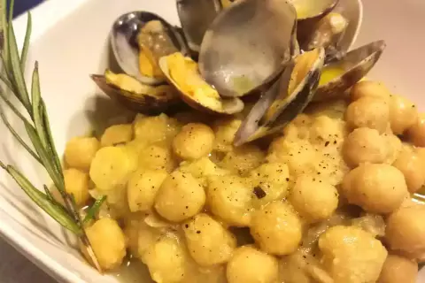 Un piatto invitante di ceci e vongole, condito con erbe aromatiche e pepe nero.
